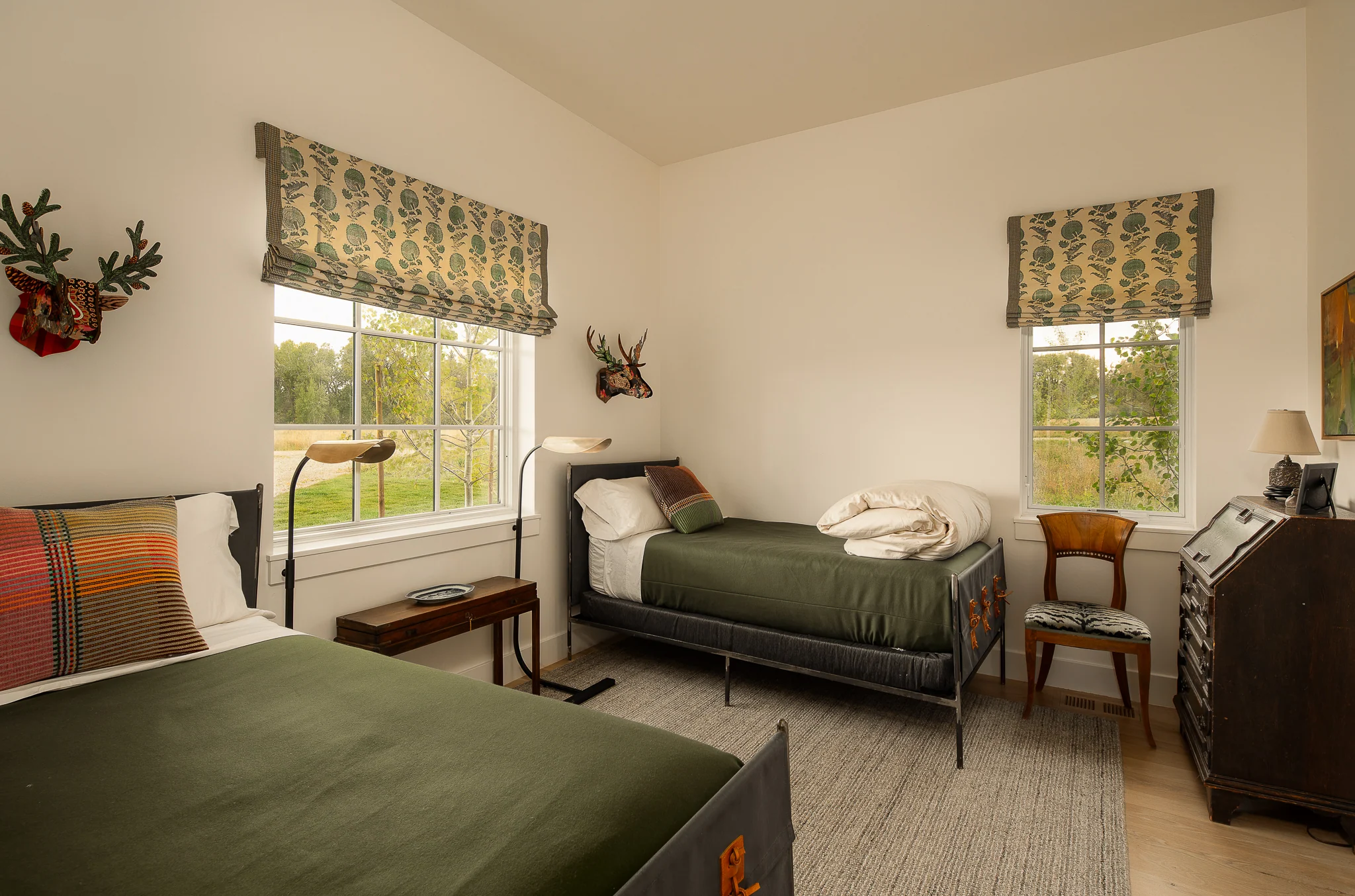 Twin bedroom with taxidermy deer mounts and patterned blankets — interior design photography Driggs Idaho, River's Edge
